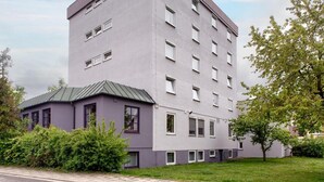 Um edifício de vários andares com telhado plano e um pequeno anexo com telhado verde.