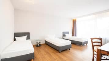 Una camera d'albergo moderna con due letti singoli, un tavolino e una sedia.