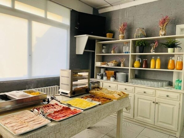 Un bufé de desayuno con diversos alimentos, una máquina de café y estantes con utensilios de cocina y objetos decorativos.