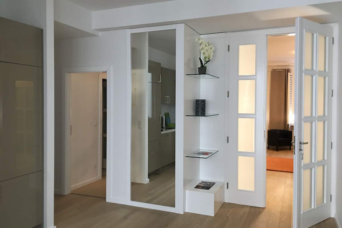 Un intérieur moderne comprenant une cuisine, des étagères ouvertes et une porte donnant sur une autre pièce.