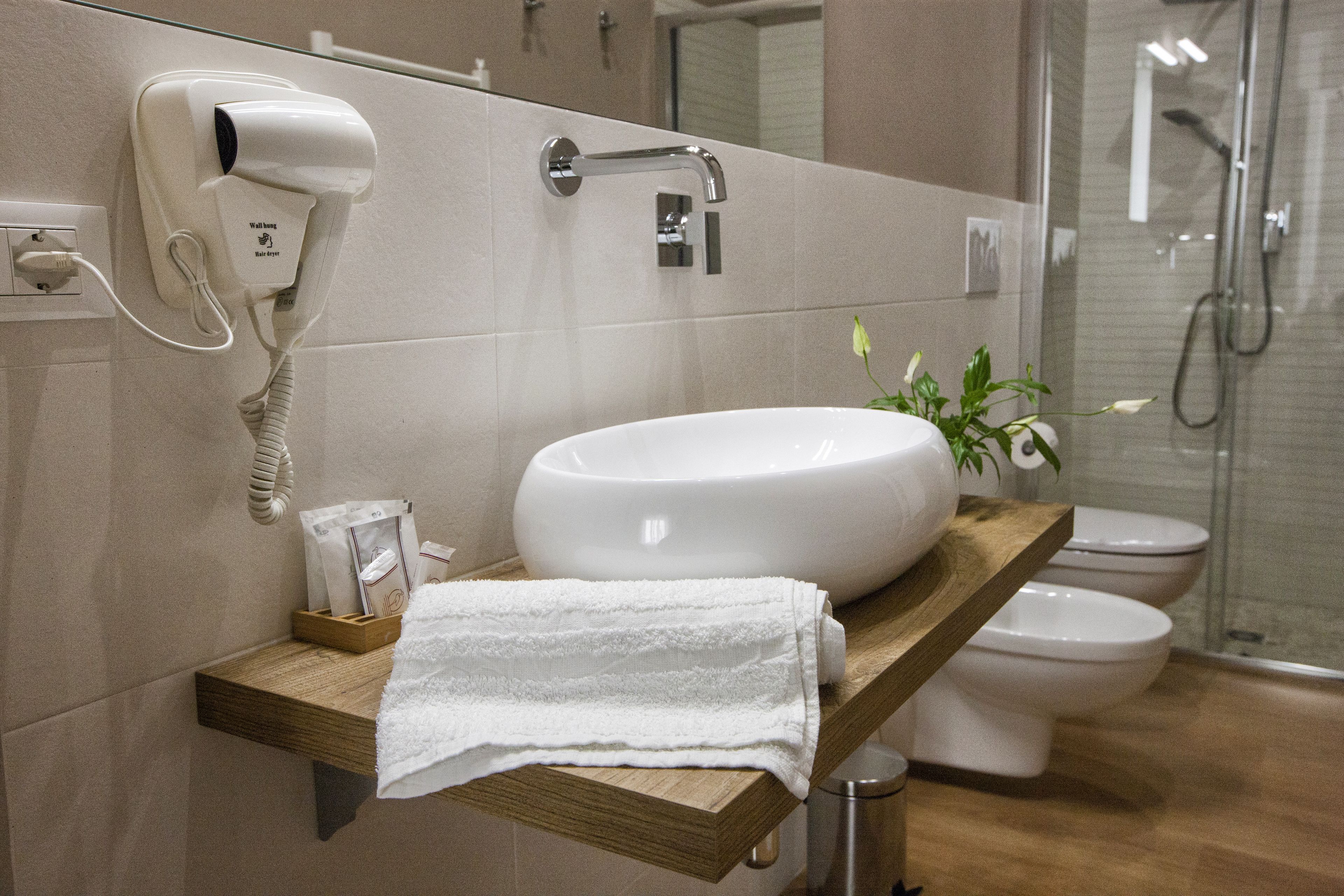 Casa de banho com lavatório branco, secador de cabelo, toalha e zona de duche.
