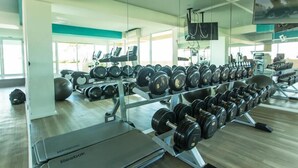 Un gimnasio con filas de mancuernas, cintas de correr y equipo de ejercicio.