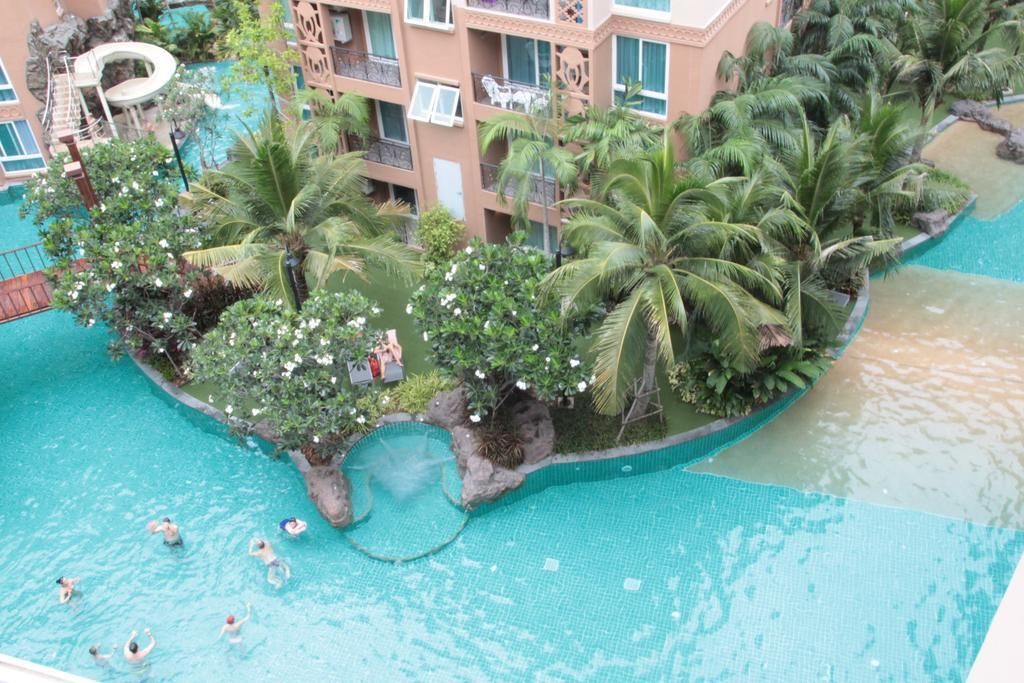 A pool area with palm trees and a water slide.