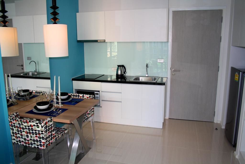 A modern kitchen with white cabinets, a black countertop, and a dining area with a table set for four.