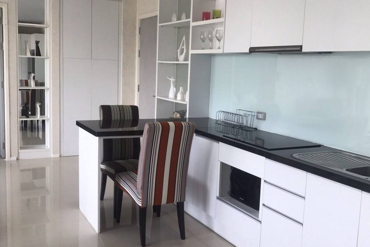A modern kitchen with white cabinetry, a black countertop, and a striped chair.