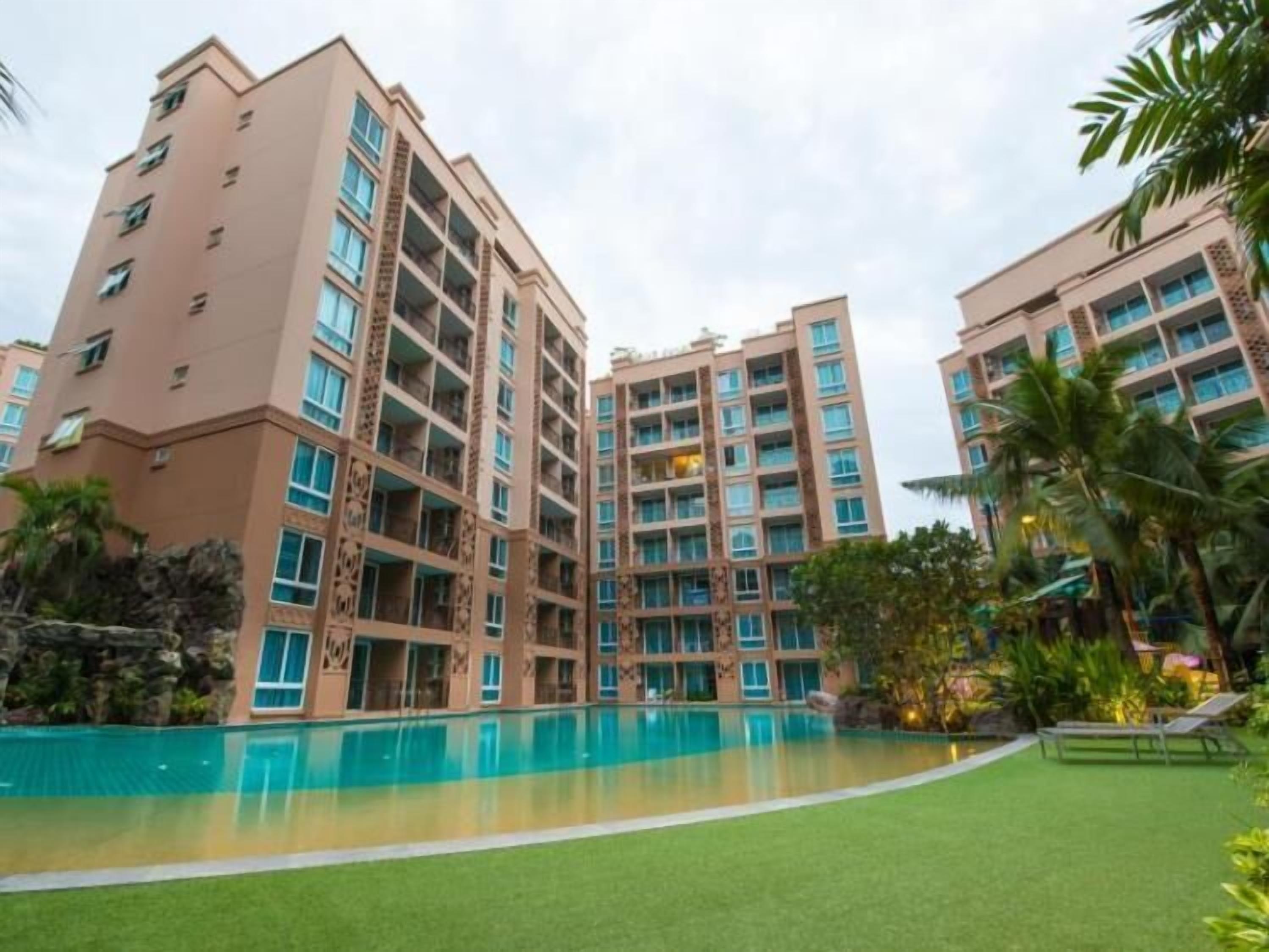 A multi-story hotel with a swimming pool and lush greenery.