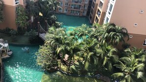 Un edificio de varios pisos con una piscina central rodeada de palmeras.
