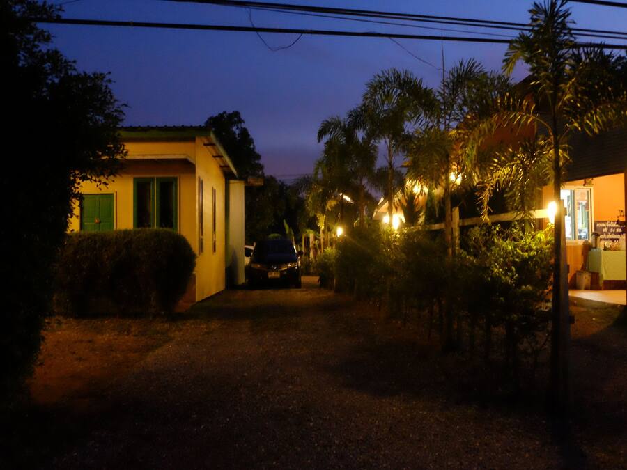 A nighttime view of a building with a car parked in front, surrounded by vegetation and illuminated by streetlights.