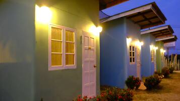 Una hilera de edificios azules con puertas y ventanas blancas, cada uno iluminado por luces en la pared.