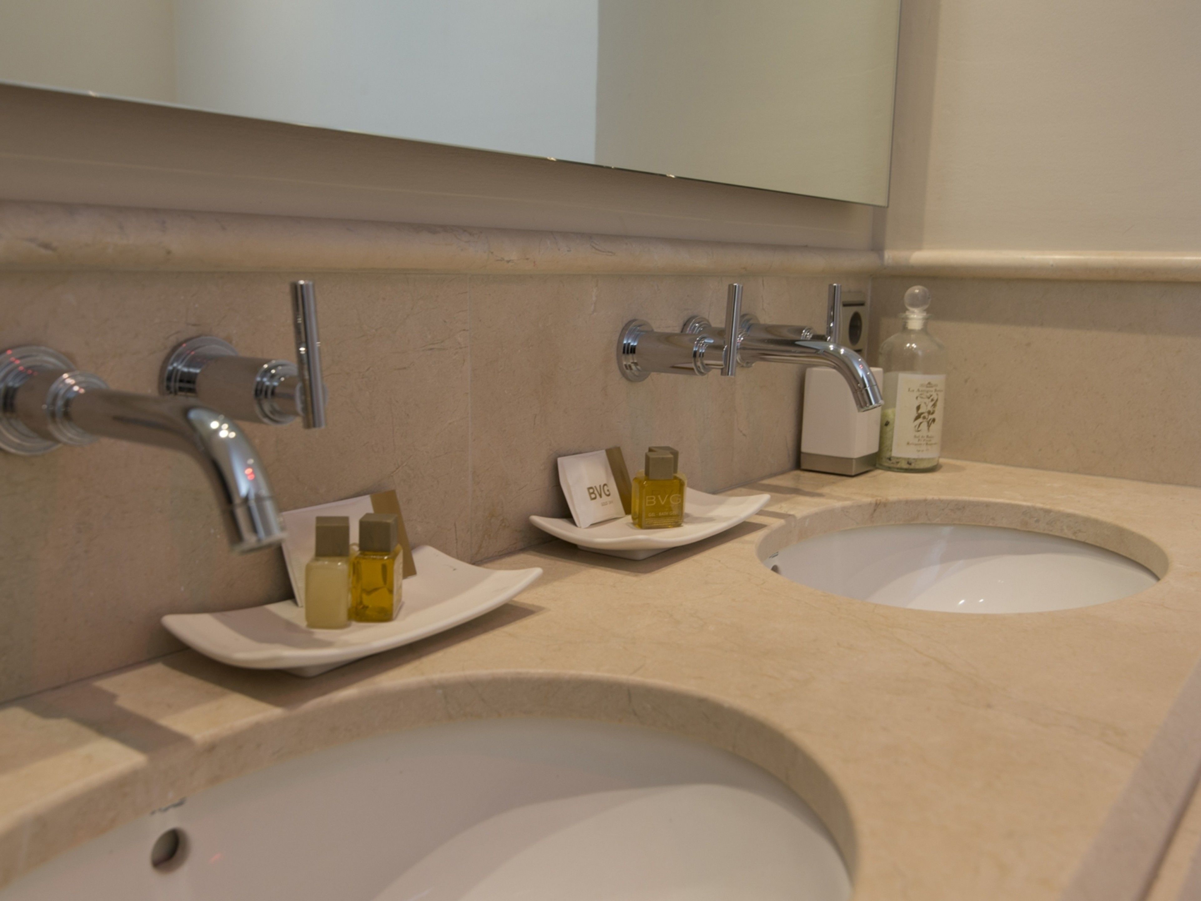 A bathroom with two sinks, a mirror, and toiletries on the counter.