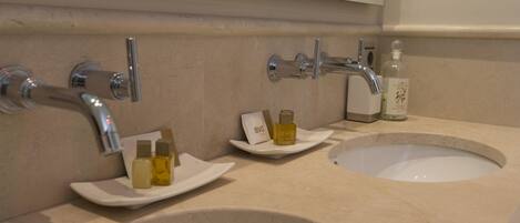 A bathroom with two sinks, a mirror, and toiletries on the counter.