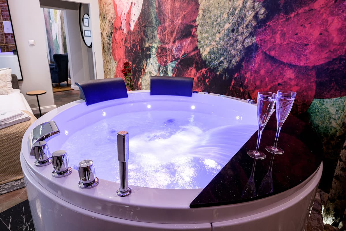A hot tub with a table, four chairs, and three champagne flutes.