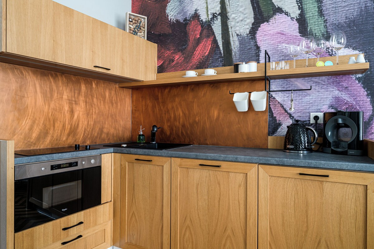 A modern kitchen with wooden cabinets, a built-in oven, and a coffee maker on the countertop.