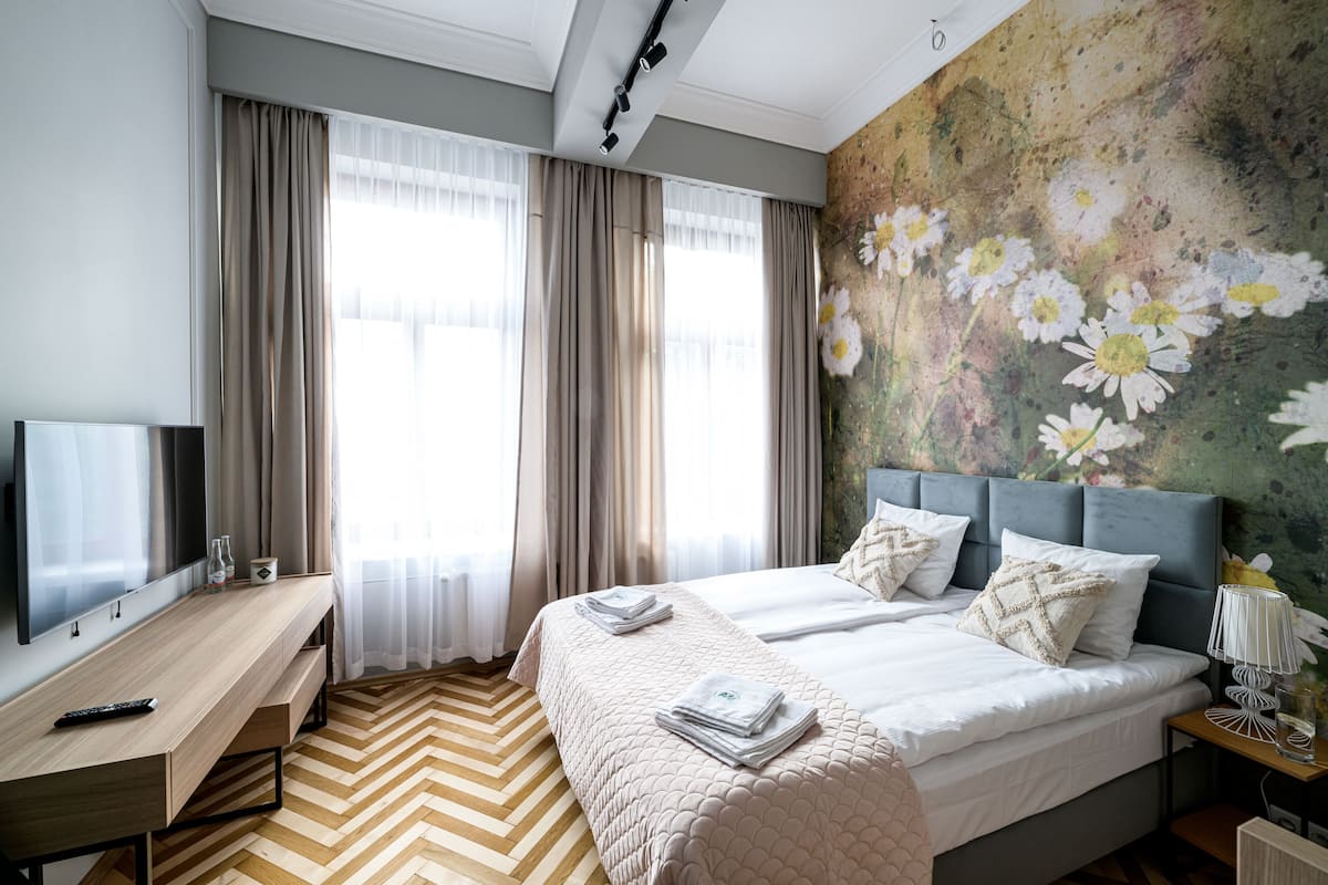 A modern hotel room with a large bed, a desk, and a television.