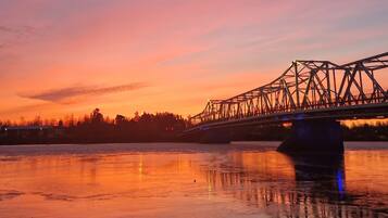 A bridge over a frozen body of water with a sunset in the background.