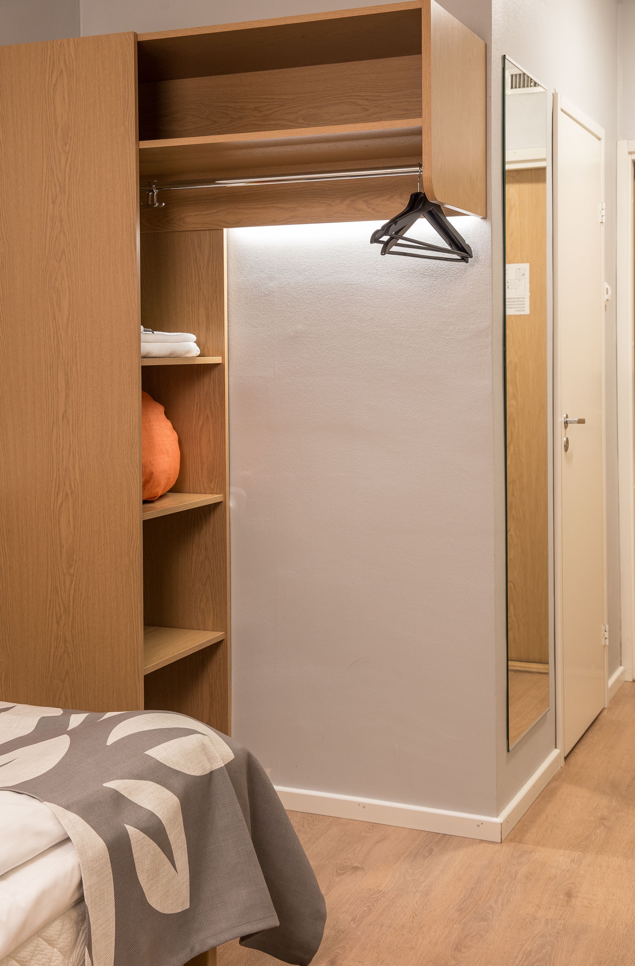 A bedroom with a bed, a wardrobe, and a mirror.