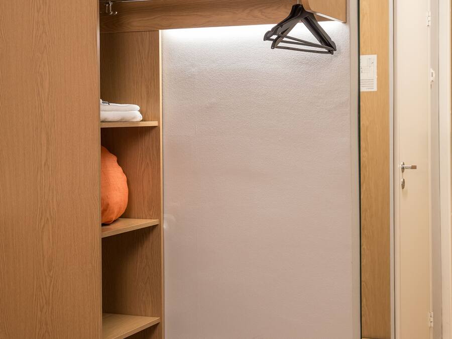 A bedroom with a bed, a wardrobe, and a mirror.