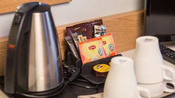 Una estación de café con una tetera, bolsitas de té Lipton y tazas blancas sobre una mesa.
