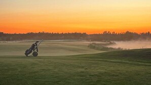 A golf course at sunset with a golf cart in the foreground. - Park Hotel Tornio (Tornio)