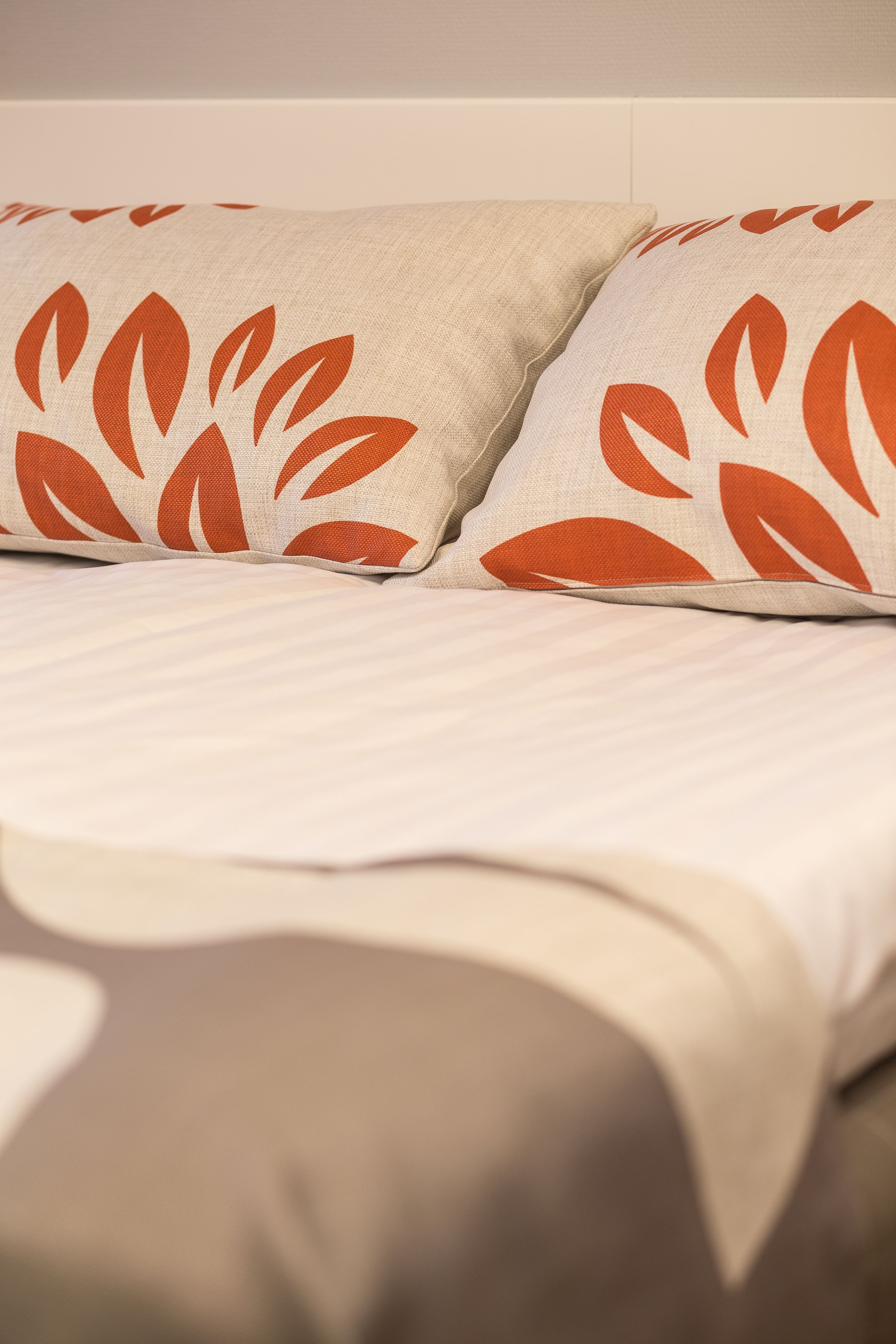 Een bed met twee kussens met een bladmotief.