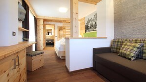 Un intérieur en bois comprenant un lit, un canapé et un téléviseur posé sur un meuble en bois.