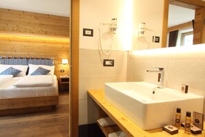 A wooden bed with pillows, a bedside table, a white sink, and a mirror.