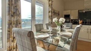 A dining area with a glass table, chairs, and a vase of flowers. - Your Space Apartments - The Hamilton's (Cambridge)