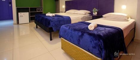 A hotel room with two beds, a wardrobe, a desk, and a small fridge.