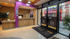 A hotel reception area with a reception desk, a purple wall, and a sign indicating 'Reception'. - Rede Andrade Docas (Belém)