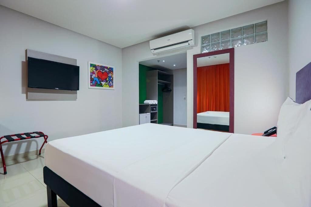 A hotel room with a bed, a television, a wardrobe, and a bathroom visible through an open door.