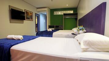 A hotel room with two beds, a flat-screen TV, an air conditioning unit, and a green accent wall.