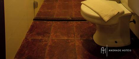 A bathroom with a glass-enclosed shower, a toilet, and a tiled floor.