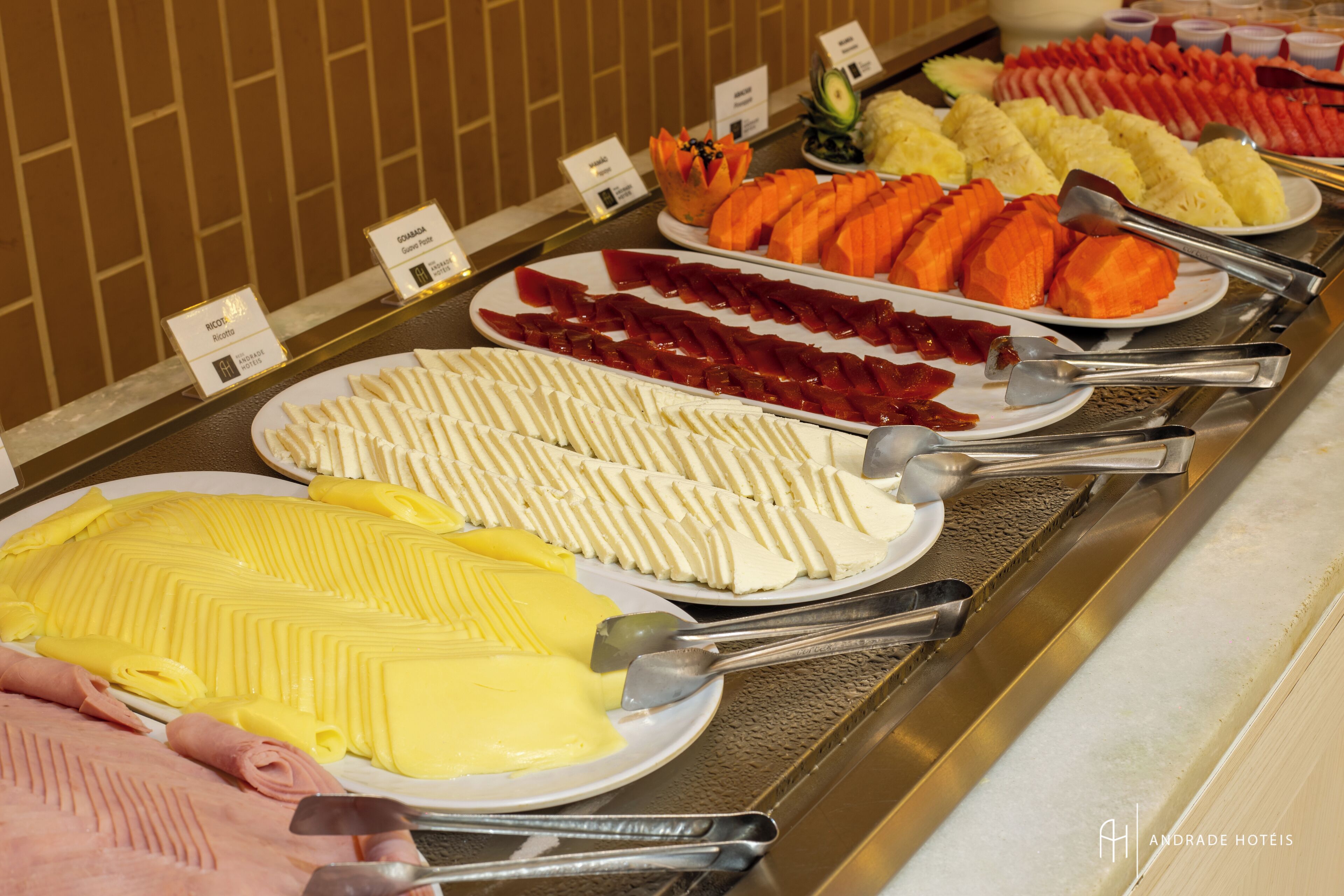 En buffet med forskellige spiser, herunder skiveskåret kød, oste og frugt.