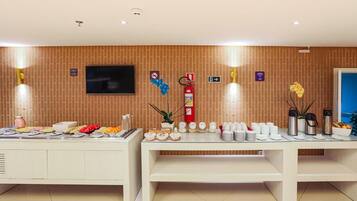 A buffet setup with various food items and a fire extinguisher on the wall.