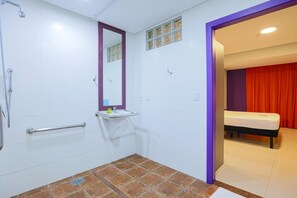 Une salle de bain avec une douche, un lavabo, un miroir et des toilettes. Il y a un rideau rouge dans la pièce adjacente.