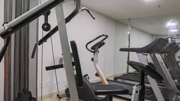Uma academia com diversos equipamentos de exercícios, incluindo um suporte para barra, esteiras e aparelhos de musculação.