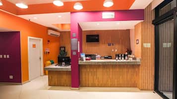 Un espace d’accueil comprenant un comptoir de réception en bois, un téléviseur fixé au mur et un panneau indiquant l’emplacement de la réception.