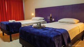 A hotel room with two beds, each with a blue blanket, white pillows, and a bottle of champagne. - Rede Andrade Docas (Belém)