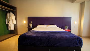 Una habitación de hotel moderna con una cama grande, una bata colgada en un perchero y una pequeña mesa con un florero.