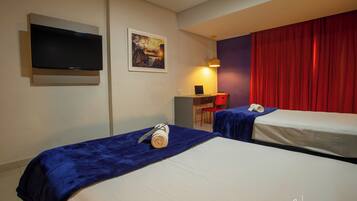 A hotel room with two beds, a desk, a chair, a television, and a red curtain.