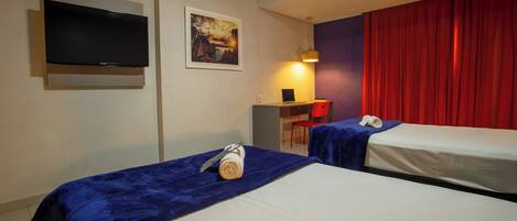 Habitación de hotel con dos camas, un escritorio, una silla, un televisor y una cortina roja.