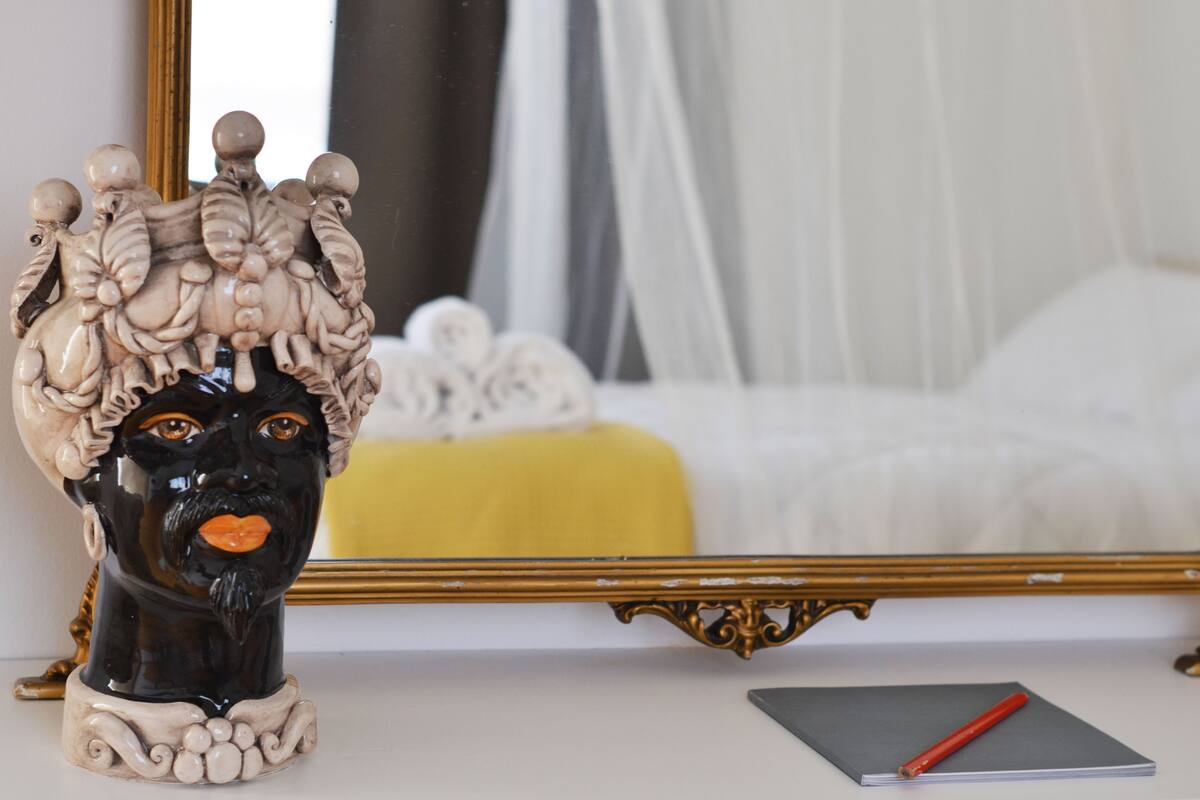 A decorative ceramic bust on a table with a notebook and pencil beside it.