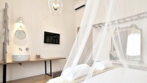 A modern bedroom with a bed, a bedside table, a mirror, and a wall-mounted TV. - Lo spazio di Mima (Noto)