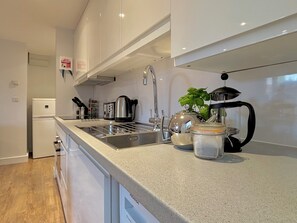 Uma cozinha moderna com uma pia de aço inoxidável, chaleira, torradeira e geladeira.