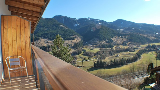 A balcony with a wooden railing overlooking a mountainous landscape. - Albergo Lucia (Tesero)