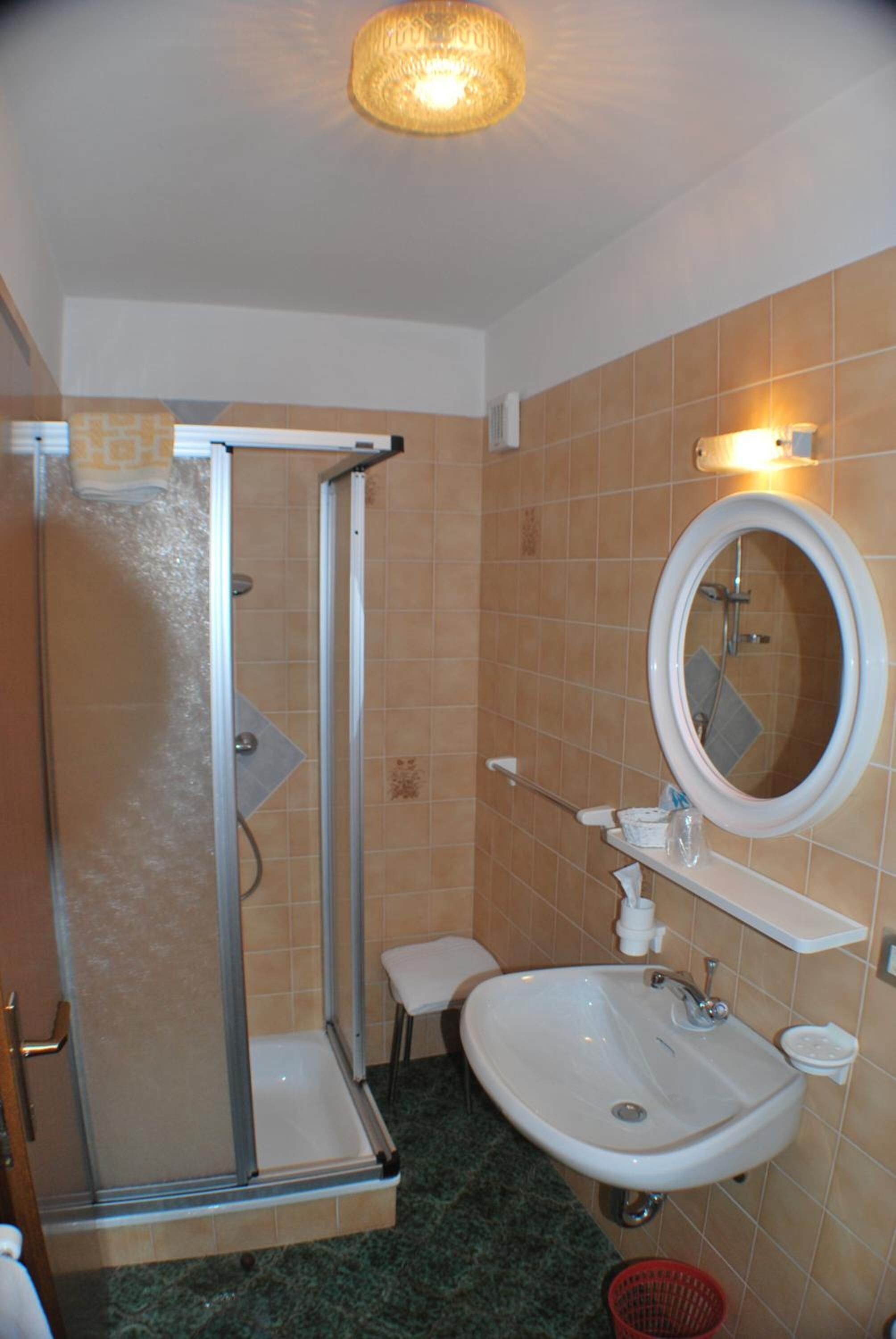 Un bagno con doccia, lavandino e specchio.