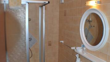 Un bagno con doccia, lavandino e specchio.
