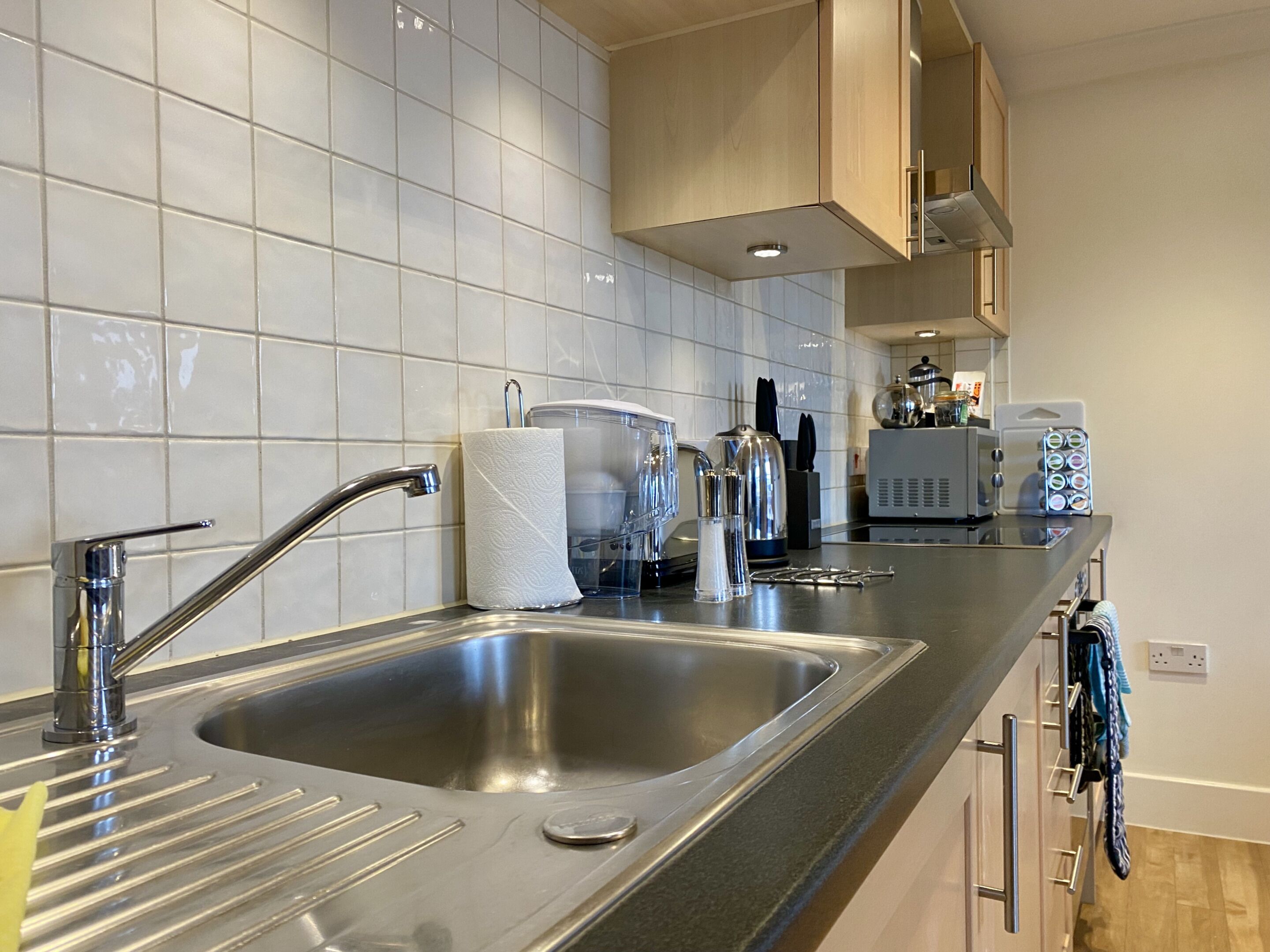 A modern kitchen with stainless steel sinks, a paper towel holder, and a coffee machine.