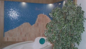 A bathroom with a bathtub, a mosaic wall, and a potted plant. - Albergo Pozzole (Tesero)