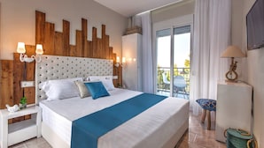Une chambre d’hôtel avec un grand lit, une tête de lit en bois, des tables de chevet blanches, un coussin décoratif bleu et un balcon avec une chaise.